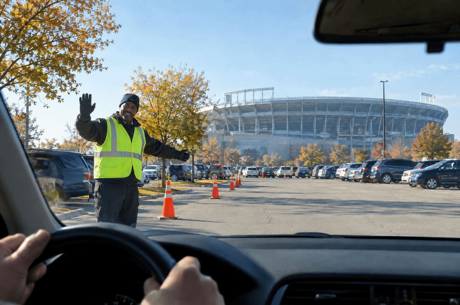 Car pulling into a stadium parking lot as an attendant waves it through